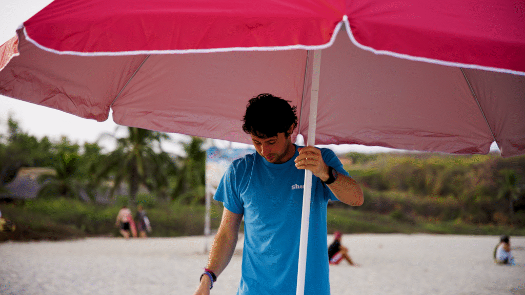 Mack Linstead, Beach Sherpa Founder, holding a red umbrella that he has carried to the beach for a client.